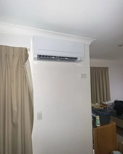Wall-mounted split-system indoor head installed above the window line in a living room